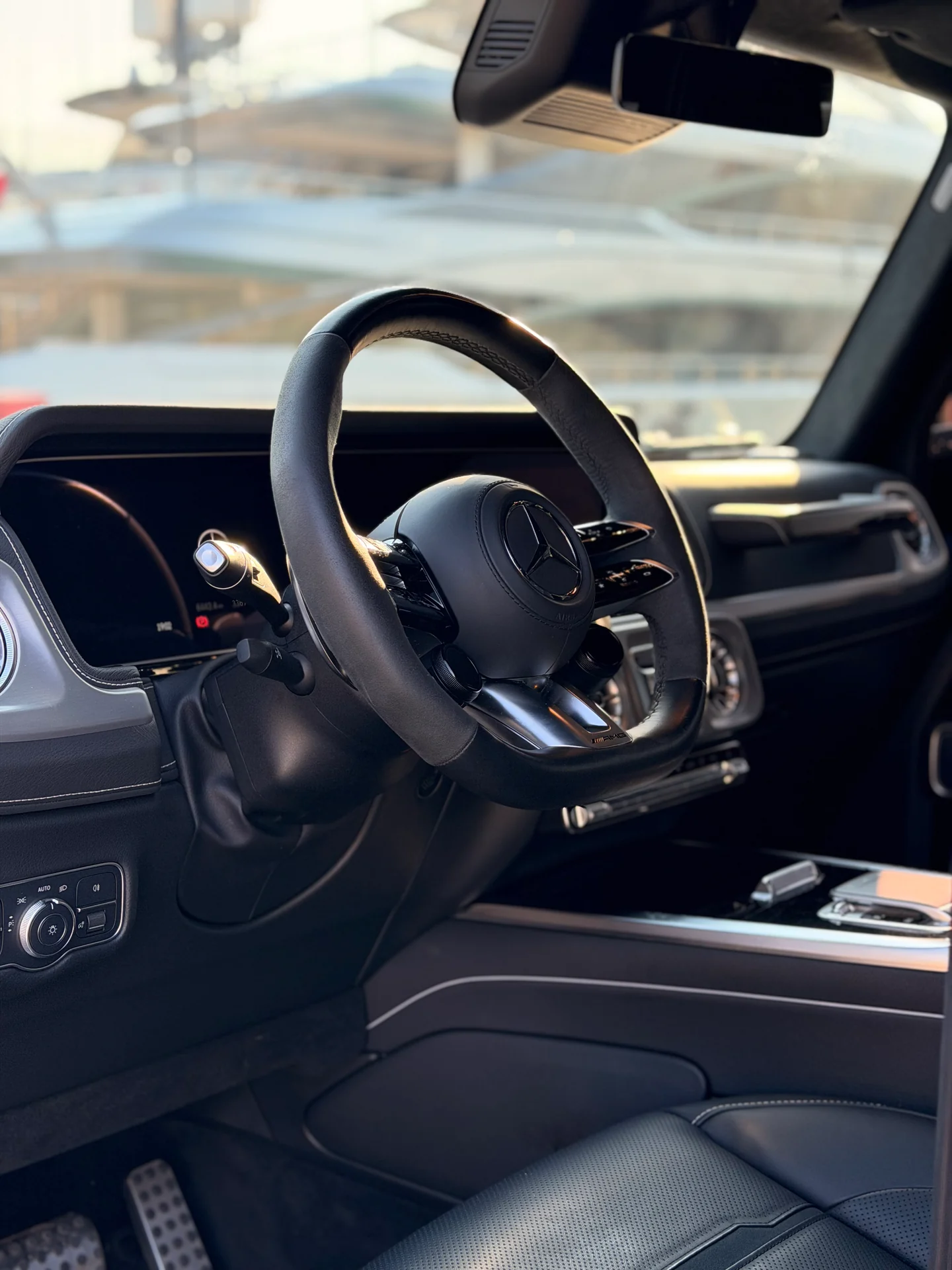 Abitacolo scuro della Mercedes-AMG G63 con volante, plancia e sedile anteriore