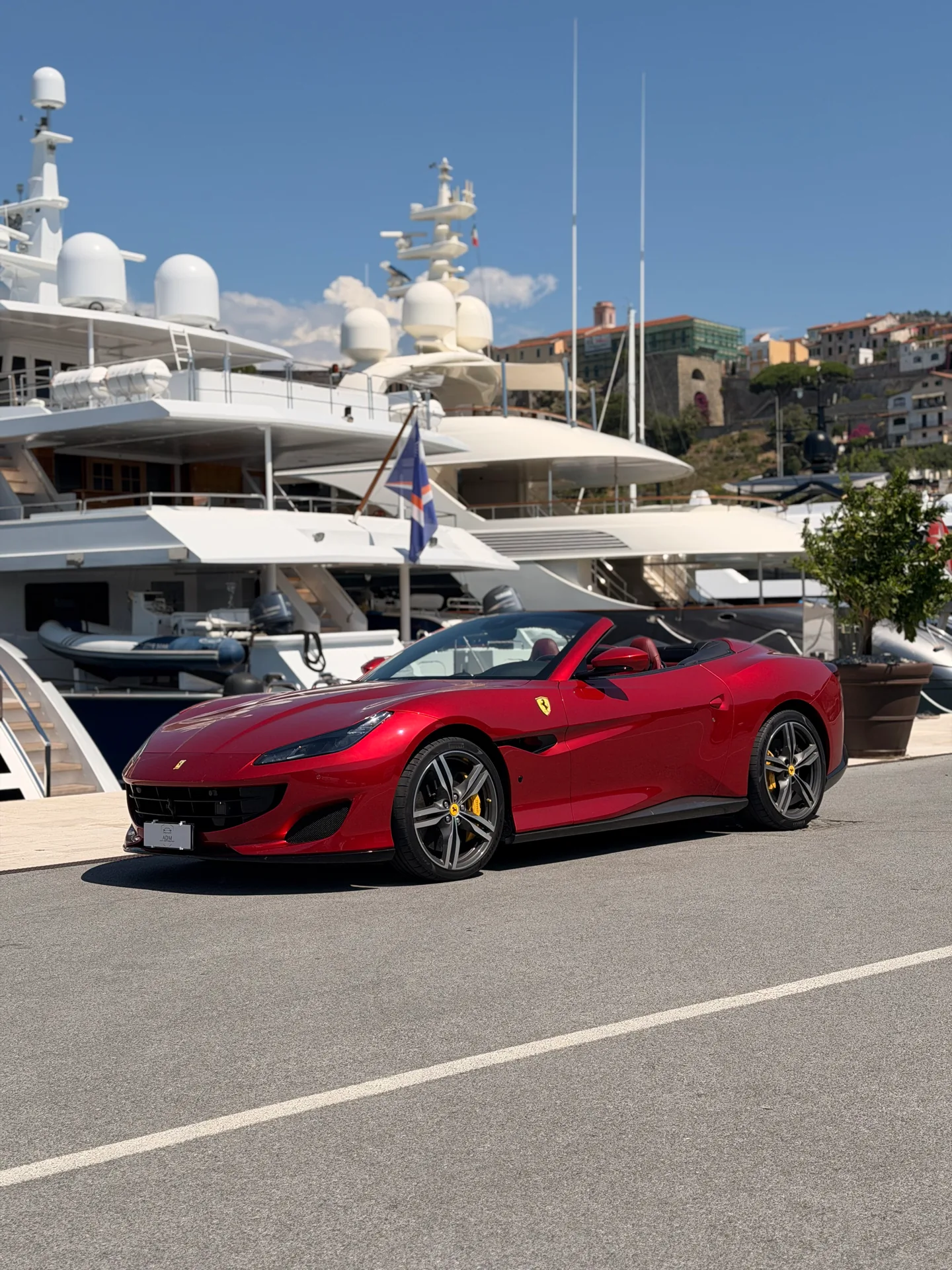 Ferrari Portofino rossa a tetto aperto, vista di tre quarti anteriore in porto.
