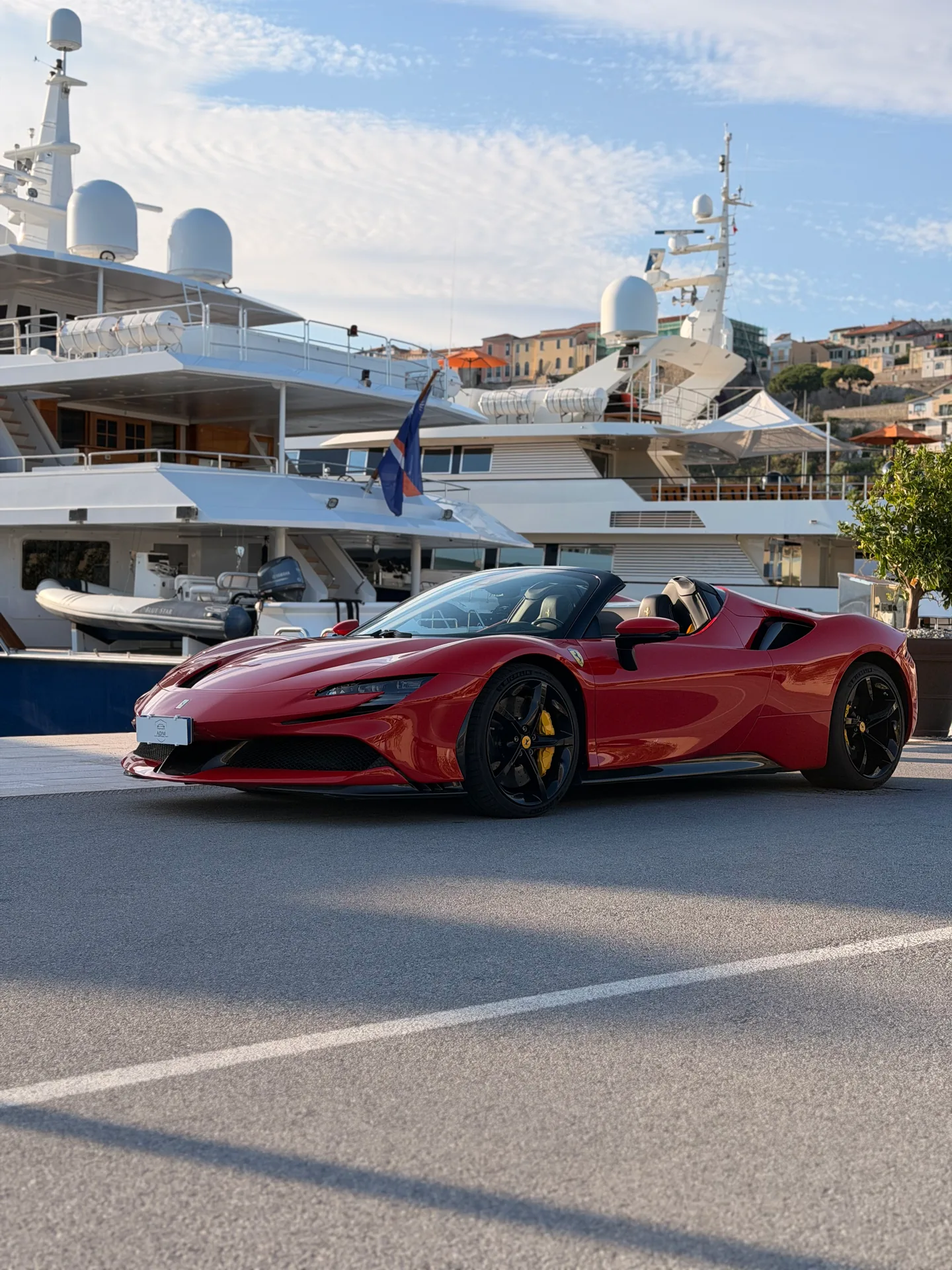 Ferrari SF90 rossa a tetto aperto, vista di tre quarti anteriore in porto.
