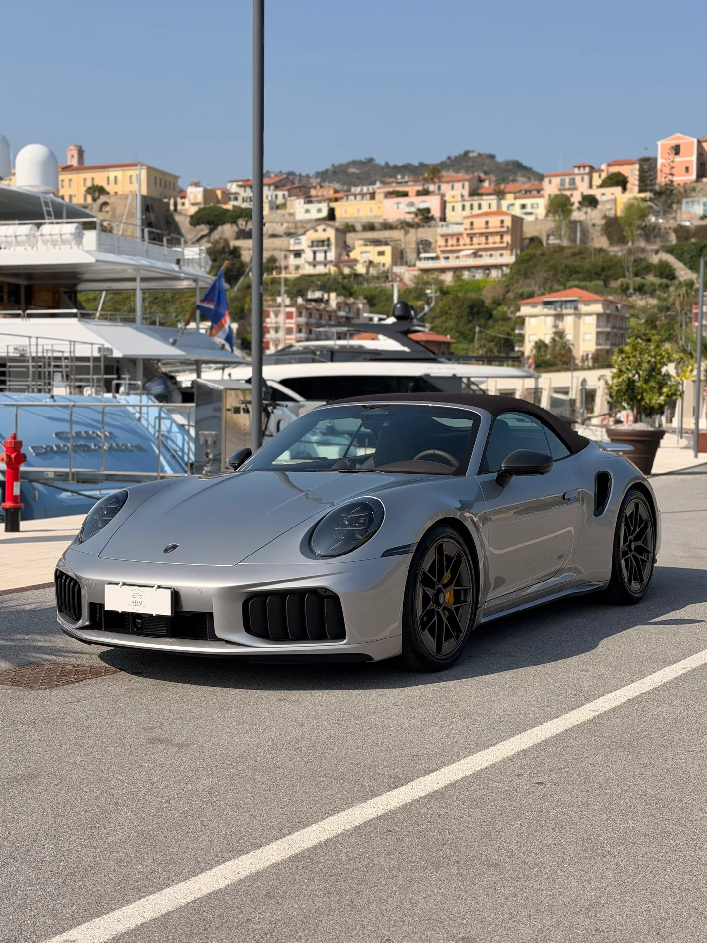 Porsche 911 Turbo S argento con tetto scuro, vista di tre quarti anteriore in porto.